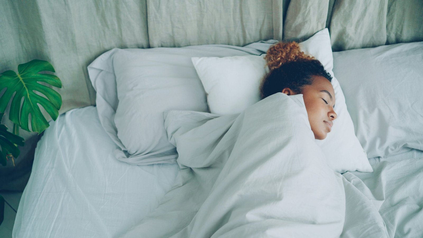 A young woman sleeping peacefully in a white bed.